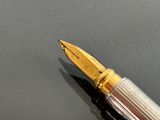 a fountain pen sitting on top of a black surface