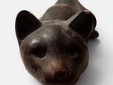 sculpture of a cat laying down on a white surface
