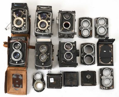 Plusieurs anciens appareils photo sont alignés sur une surface blanche