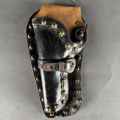 a black leather holster with brass studding and a leather belt