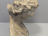 marble bust of a woman with curly hair on a table