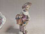 a figurine of a woman with a basket of flowers