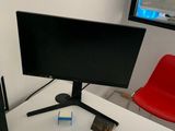 un écran d'ordinateur posé sur un bureau à côté d'une chaise rouge