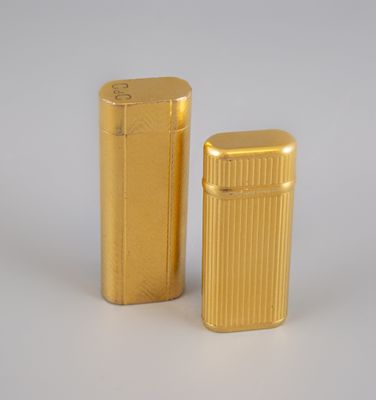 two gold lighters sitting next to each other on a white surface