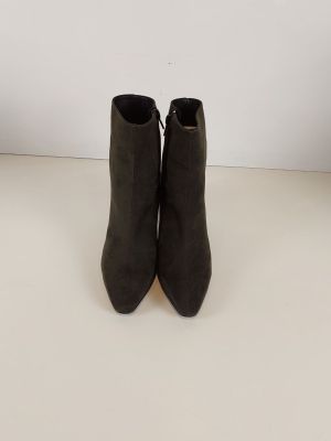une paire de bottines en daim noir posées sur une surface blanche