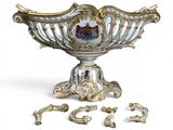 un bol blanc et doré posé sur un socle, à côté d'autres bijoux