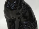 a black cat statue sitting on a white surface