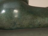 a bronze statue of a woman laying down on a table