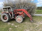 un tracteur rouge garé dans l'herbe