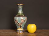 a vase and an apple sitting on a table