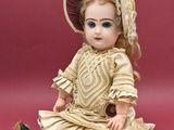 a doll that is sitting on the ground with a hat on