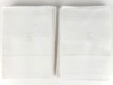 two white towels with embroidered monograms on them on a white surface