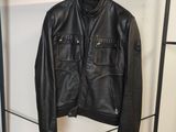 une veste en cuir noir suspendue à un cintre dans une pièce