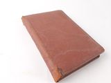 an old book with a brown cover sitting on top of a white table