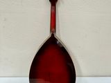 a red mandolin sitting on top of a table next to a white wall