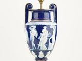 a blue and white vase on a table with a light on it