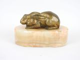 statue d'un lapin posée sur un socle en marbre, sur fond blanc
