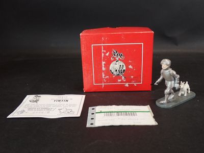 figurine en argent représentant un homme avec un chien devant une boîte rouge