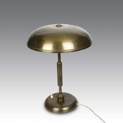 a brass table lamp with a white cord on a grey background