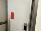 a white door with a red sticker on it in a bathroom