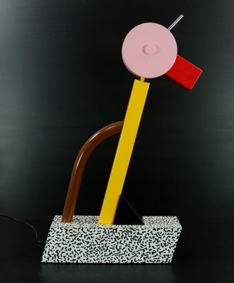 une sculpture en bois représentant un objet rose et jaune posé sur une surface noire