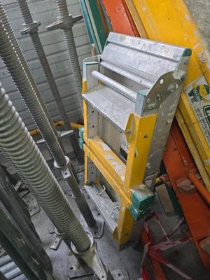 un tas de tuyaux métalliques posé par terre à côté d'un bâtiment