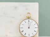un bloc de marbre blanc sur lequel repose une montre de poche en or