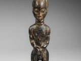 une petite statue en bois représentant un homme coiffé d'un chapeau