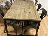 a wooden table with chairs and a chalkboard on the wall