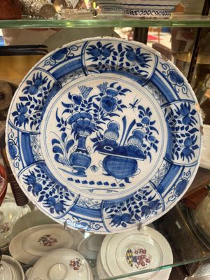 a blue and white plate on display in a glass case