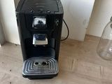 a black coffee maker on a wooden table next to a window