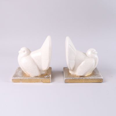 une paire de colombes en céramique blanche posées sur des socles en marbre, sur fond blanc