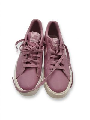 des baskets violettes avec des lacets sur le dessus, posées sur une surface blanche
