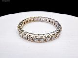 a close up of a diamond eternity ring on a white surface