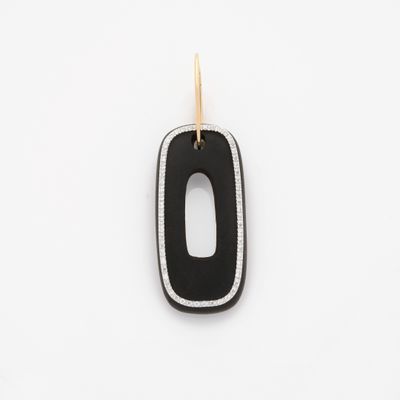 un gros plan d'un pendentif noir et blanc posé sur une surface blanche