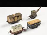 quatre wagons de train miniature sont alignés sur une surface blanche