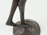 bronze statue of a woman standing on a rock with her hands on her hips