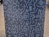 un réfrigérateur noir recouvert de graffitis, dans un entrepôt