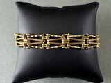 a close up of a gold bracelet on a black pillow