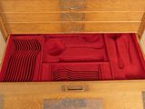 a wooden box with red napkins and silverware in it