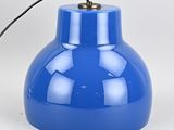 une image représentant une lampe bleue posée sur une surface blanche
