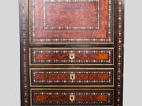 an antique chest of drawers with a wooden top and gold trimmings