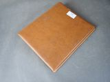brown leather notebook with a label on it on a gray surface