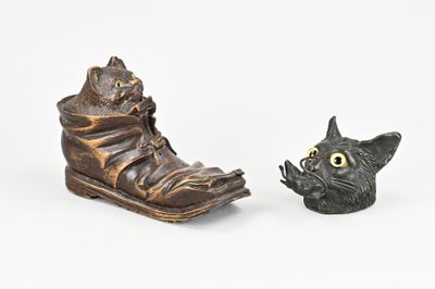 deux figurines représentant un chat et une chaussure posées sur une surface blanche