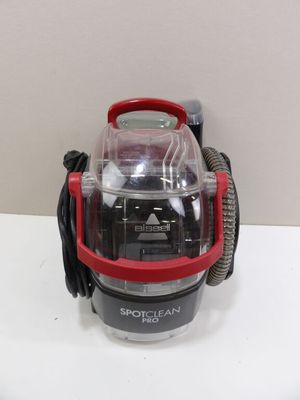un petit aspirateur rouge et noir posé sur une table blanche