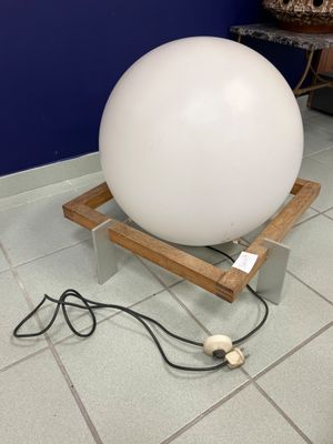 une grosse boule blanche posée sur un socle en bois au sol