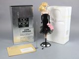 barbie doll in a black dress next to a box of perfume