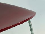 un gros plan d'une chaise rouge devant un mur blanc