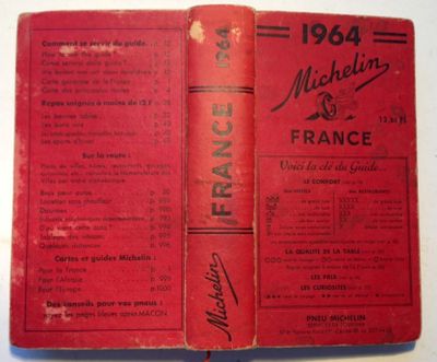 an old book with a red cover sitting on top of a table