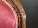 a close up of a red chair with a wooden frame